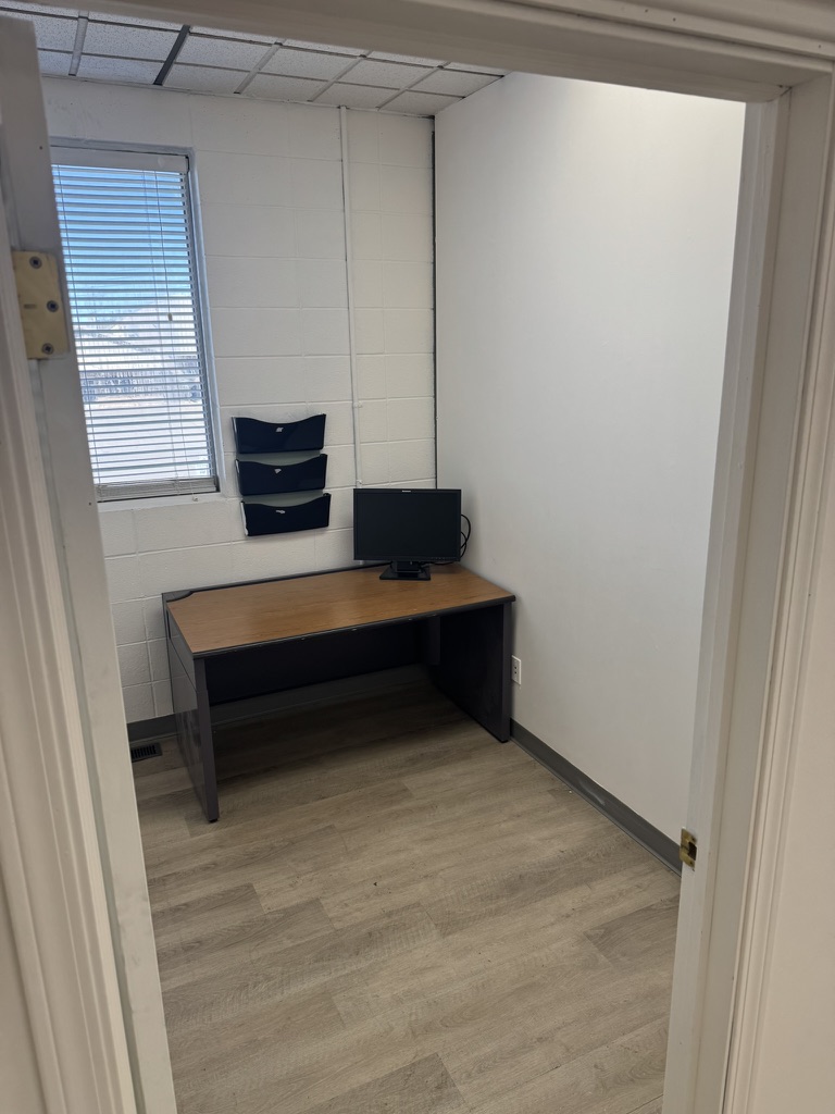 Private office at River Ave with single desk, monitor, wall file organizer, and window